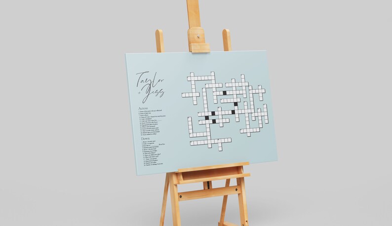 May include: A light blue crossword puzzle on an easel with the text "Taylor + Jess" at the top. The puzzle has a list of clues for "Across" and "Down" on the left side.