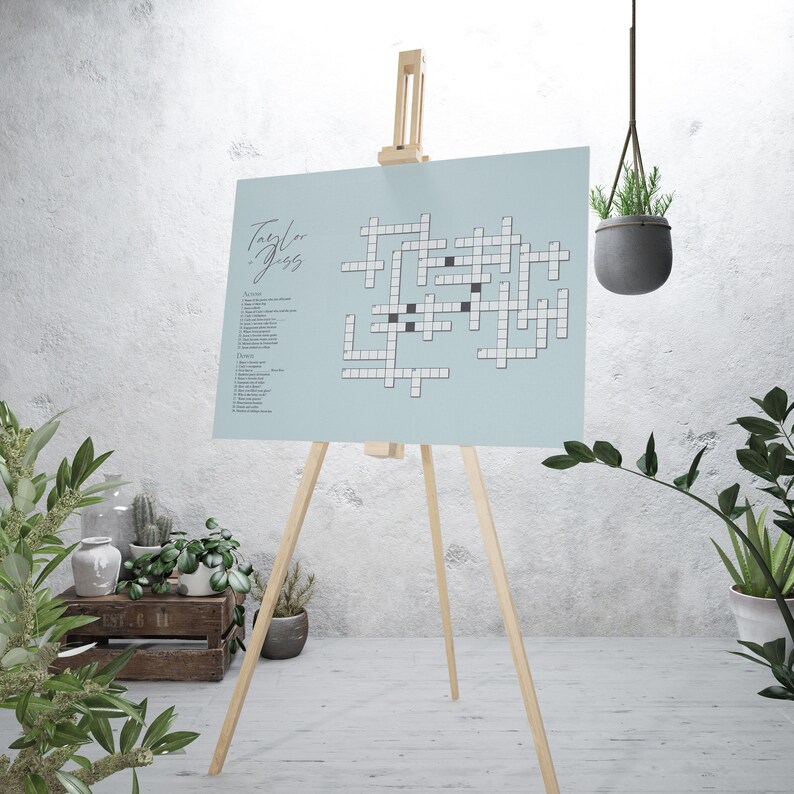 A powder blue crossword puzzle is shown displayed on an easel in a well-lit room, ready for party guests to solve