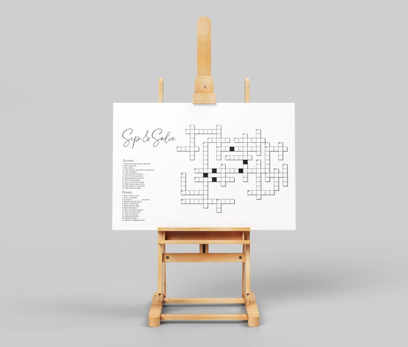 May include: A white crossword puzzle on an easel with the title "Sip & Solve". The puzzle has a grid of squares with black squares for clues. The puzzle is on a white background.