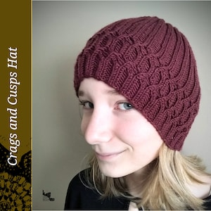 May include: A close-up of a person wearing a maroon knitted hat with a textured pattern. The hat is slouched on the person's head, and the person is looking to the side.