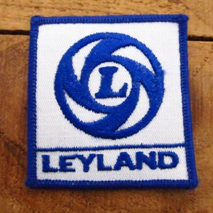 May include: Blue and white embroidered patch with the Leyland logo. The logo features a stylized letter L inside a blue circle with a swirling pattern.