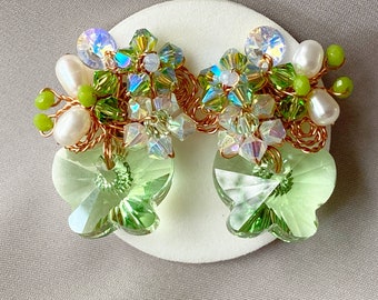 May include: A pair of green crystal butterfly earrings with a floral design made of iridescent beads and pearls.