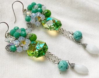 May include: A pair of green and white crystal earrings with a floral design and a dangling crystal charm. The earrings are made with silver wire and beads.