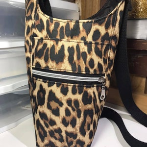May include: A brown and black leopard print crossbody bag with a black strap and a silver zipper.