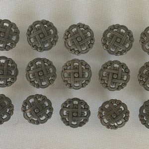 May include: A set of 16 antique-style metal cabinet knobs with a decorative, intricate design. The knobs are a dark gray color and have a circular shape.