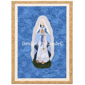 May include: A rectangular fabric wall hanging featuring a central applique of a figure in a white veil and robe, draped in a blue patterned shawl. The figure holds a rosary with a cross, standing on a green base against a blue floral background.