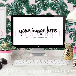 May include: A white computer monitor with a blank screen displaying the text "your image here" on a pink and green tropical leaf patterned background. The monitor is on a white marble desk with a white keyboard, a gold pineapple, a pink flamingo, and other office supplies.