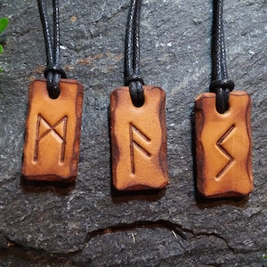 May include: Three leather pendants with black cords, each featuring a different Norse rune symbol. The runes are etched into the leather and are visible against the brown background.