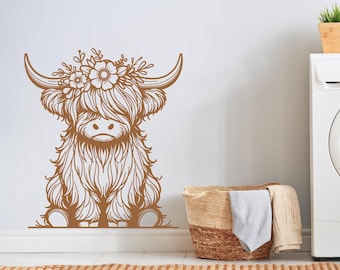 May include: A brown line drawing of a Highland cow with flowers on its head, on a white wall. A white washing machine is in the background.
