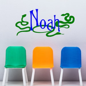 以下が含まれることがあります： 白い壁に、緑、オレンジ、青の椅子が3つ並んでいます。壁には緑色のヘビのデザインと、青い文字で「ノア」と書かれています。