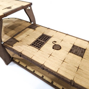 May include: A wooden model of a ship's deck with two levels. The top level features a small hatch and a circular design. The bottom level has a larger hatch and a rectangular design.