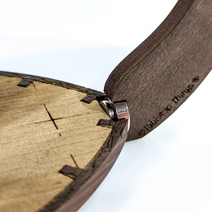 May include: Close-up of a wooden box with a hinged lid. The lid is open and the hinge is visible. The box is made of dark wood and has a light wood interior. The box is labelled "Tabletop Things".