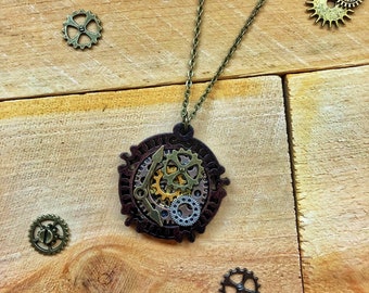 May include: A steampunk-style necklace with a circular pendant featuring a cluster of bronze and gold gears. The pendant is attached to a bronze chain.