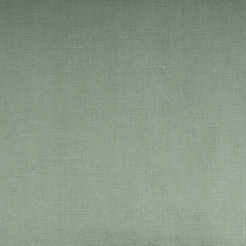 May include: A close-up of a textured, light green fabric. The fabric has a subtle woven pattern.