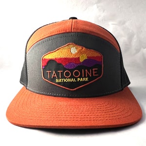 May include: A black and orange trucker hat with a patch that says "Tatooine National Park" and features a sunset scene with purple mountains and a yellow sun.