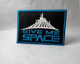 May include: A black and blue embroidered patch with a white silhouette of a roller coaster and the text "GIVE ME SPACE".