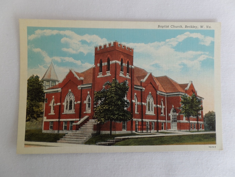 May include: A vintage postcard showing a red brick Baptist Church in Beckley, West Virginia. The church has a tall spire and a large, arched entrance. The postcard is in good condition and has a faded, vintage appearance.