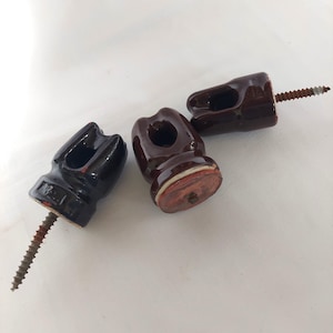 May include: Three ceramic electrical insulators with screw mounts. Two are brown with a white stripe and one is black.