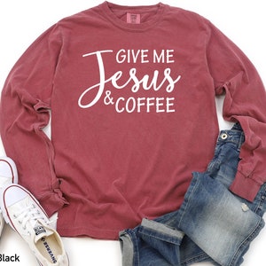 May include: A long-sleeved t-shirt with a maroon color featuring the text "Give me Jesus & Coffee" in white.