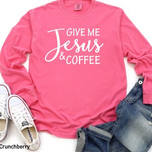 May include: Pink long-sleeve t-shirt with the text "Give me Jesus & Coffee" in white lettering.