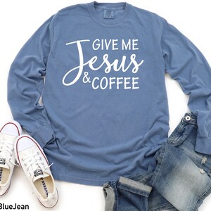 May include: A blue long-sleeved t-shirt with the text "Give Me Jesus & Coffee" in white lettering.
