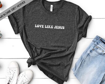 May include: A dark heather grey t-shirt with the text "LOVE LIKE JESUS" in white lettering.