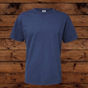 May include: A solid navy blue short-sleeved t-shirt. The shirt has a crew neck and is made of a soft, comfortable material. The t-shirt is displayed on a wooden surface.