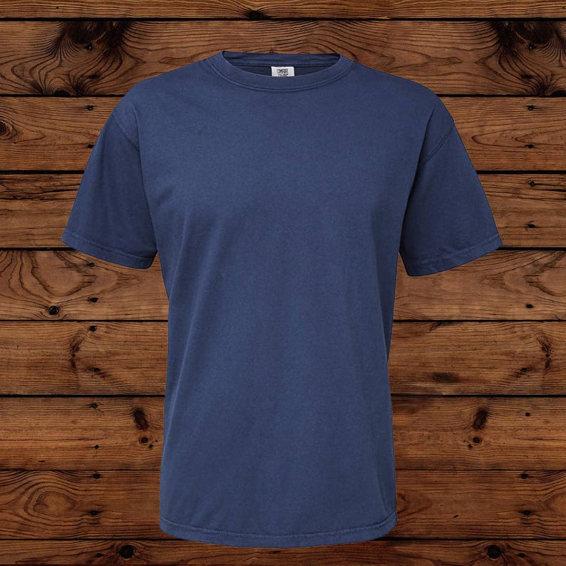 May include: A solid navy blue short-sleeved t-shirt. The shirt has a crew neck and is made of a soft, comfortable material. The t-shirt is displayed on a wooden surface.