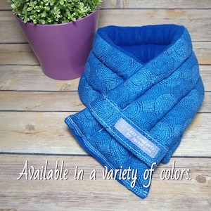 May include: Blue and white patterned microwavable neck wrap with a label that reads "Cozy Comforts by Jackie.com". Available in a variety of colors.