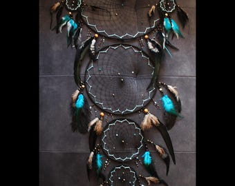 May include: A black and turquoise dreamcatcher with five hoops and feathers. The dreamcatcher is decorated with beads and has a white trim.