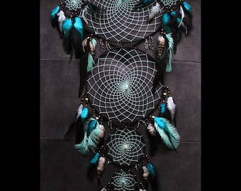 May include: A black and turquoise dreamcatcher with multiple layers of netting and feathers. The dreamcatcher is decorated with beads and has a small white bead in the center of each net.