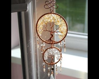 May include: A handcrafted copper wire tree of life suncatcher. The top circle features yellow citrine stones, while the bottom circle has clear quartz crystals. Dangling crystal beads and a decorative swirl complete the design. The suncatcher is suspended by a copper wire.