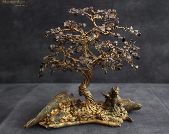 May include: A handcrafted tree sculpture with a twisted trunk and branches adorned with small, smoky quartz crystals. The tree sits on a gold-toned base with a small dragon figurine. The sculpture is approximately 8 inches tall.