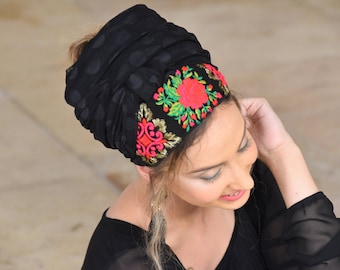 May include: Black sheer head wrap with a floral embroidered band. The band features pink, red, green, and gold embroidery.