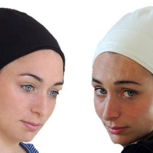 Puede incluir: Dos mujeres con cubiertas para la cabeza. Una lleva una cubierta negra y la otra una cubierta blanca.