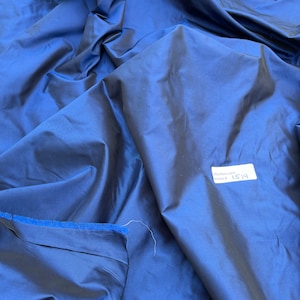 May include: A close-up of a deep blue silk fabric with a white tag that says "silkfabrics.com" and "Article # 1519".
