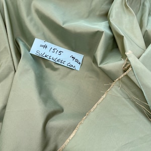 Puede incluir: Primer plano de una tela verde salvia con una etiqueta blanca que dice "#1515 silks4less.com 100% seda".