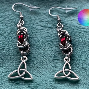May include: Silver earrings with a red bead and a Celtic knot charm.