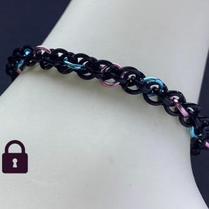 May include: Black chain bracelet with pink and blue accents. The bracelet is made of metal and has a delicate, intricate design.
