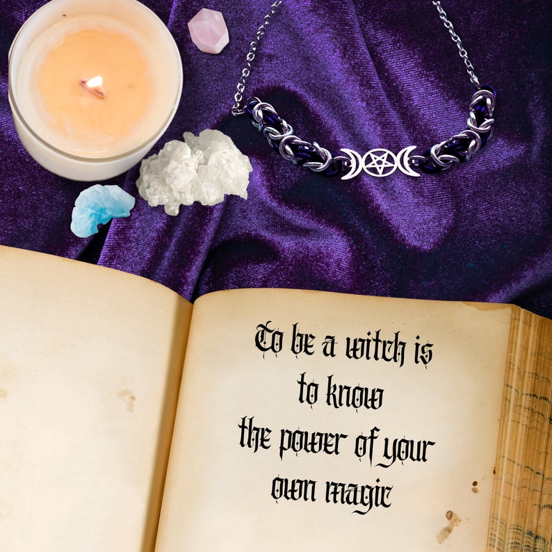 May include: An open book with the text "To be a witch is to know the power of your own magic" on a purple velvet background. There is a silver necklace with a triple moon and pentacle charm, a lit candle, and crystals on the surface.