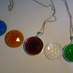 May include: Five silver necklaces with different colored glass pendants. The pendants are round and have a geometric pattern. The colors are blue, orange, red, white, and green.