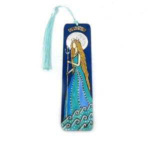 May include: A blue wooden bookmark featuring a painted image of Amphitrite, the Greek goddess of the sea. She is depicted wearing a crown and holding a trident, standing on waves. The bookmark has a blue tassel.