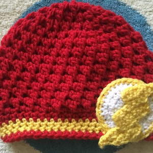 May include: Red crocheted hat with a yellow and white lightning bolt design.