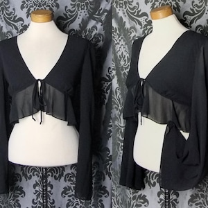May include: Black sheer long-sleeved top with a ruffled trim and a tie at the neckline.