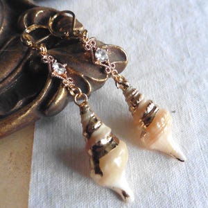 Peut inclure: Boucles d'oreilles en ton or avec un motif de coquillage et des accents de strass clairs.