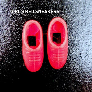 May include: A pair of bright red sneakers for a doll. The sneakers have a simple design with white stitching and a black accent on the toe.