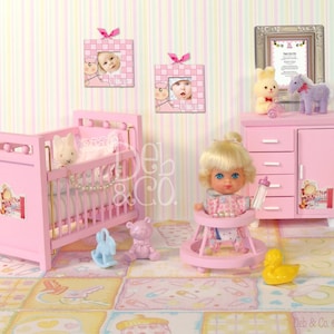 May include: A pink doll crib with a white and pink blanket, a pink doll dresser with four drawers, a pink doll walker with a doll sitting in it, and a pink doll high chair with a doll sitting in it. The doll is wearing a pink and white dress and has blonde hair. There are also several other doll accessories in the image, including a stuffed animal, a toy duck, and a bottle.