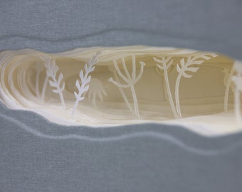 Könnte beinhalten: Eine Nahaufnahme eines Papierkunstwerks mit weißem Hintergrund und einem Ausschnitt einer Waldszene. Der Wald besteht aus übereinanderliegenden Papieren, wodurch ein 3D-Effekt entsteht.