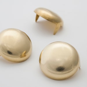 May include: Three gold-colored metal furniture feet with a round top and a pointed base.