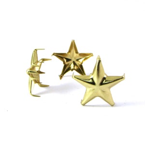 May include: Three gold metal star-shaped studs with a pointed prong on the back for attaching to fabric or leather.